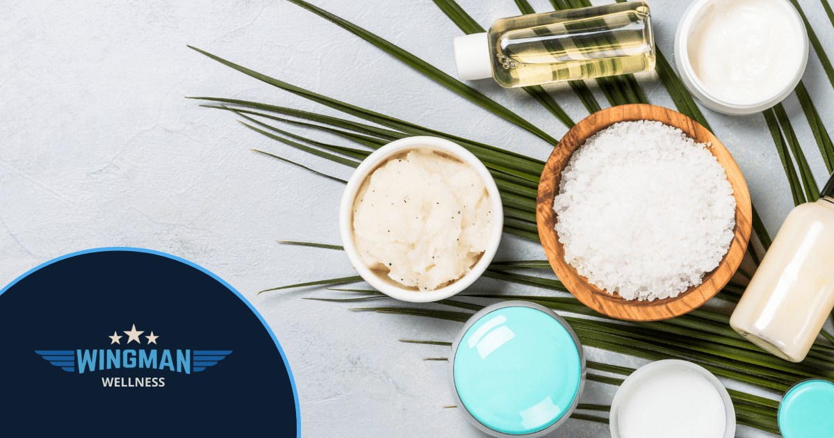 mental health - sugar scrub, cream, essential oils sitting on a palm leaf